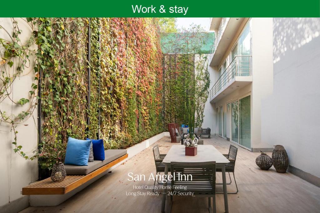 een levende muur met een tafel en stoelen voor een gebouw bij Capitalia San Angel Inn in Mexico-Stad