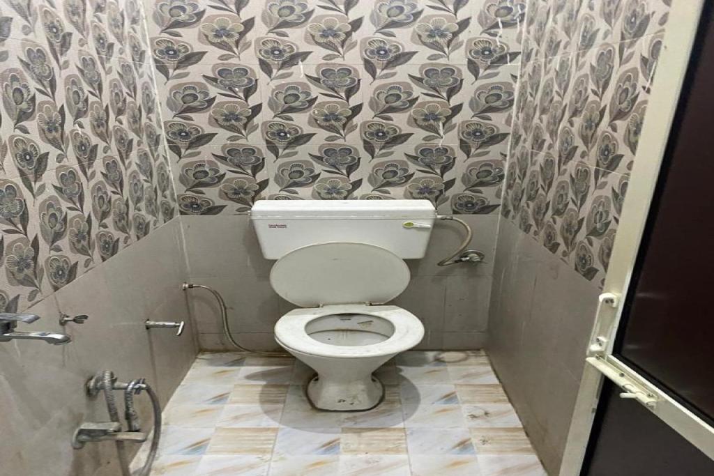 a small bathroom with a toilet in a stall at Hotel O Sun Rahi in Purainī