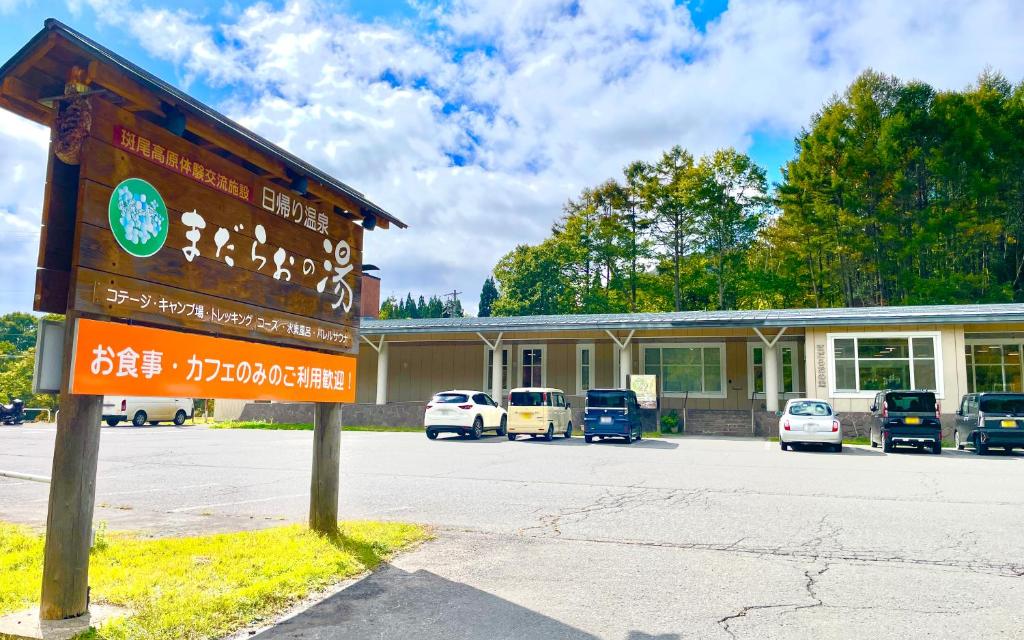 a sign in front of a building with parked cars at まだらおの湯 in Nakano
