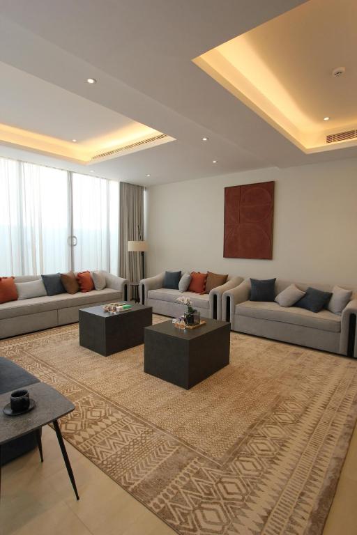a living room with couches and tables on a rug at Luxurious suite with a terrace overlooking KAFD in Riyadh