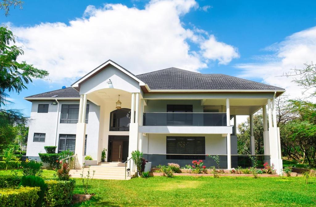 una casa bianca con un cortile verde di Atambo's Crescent a Ngong