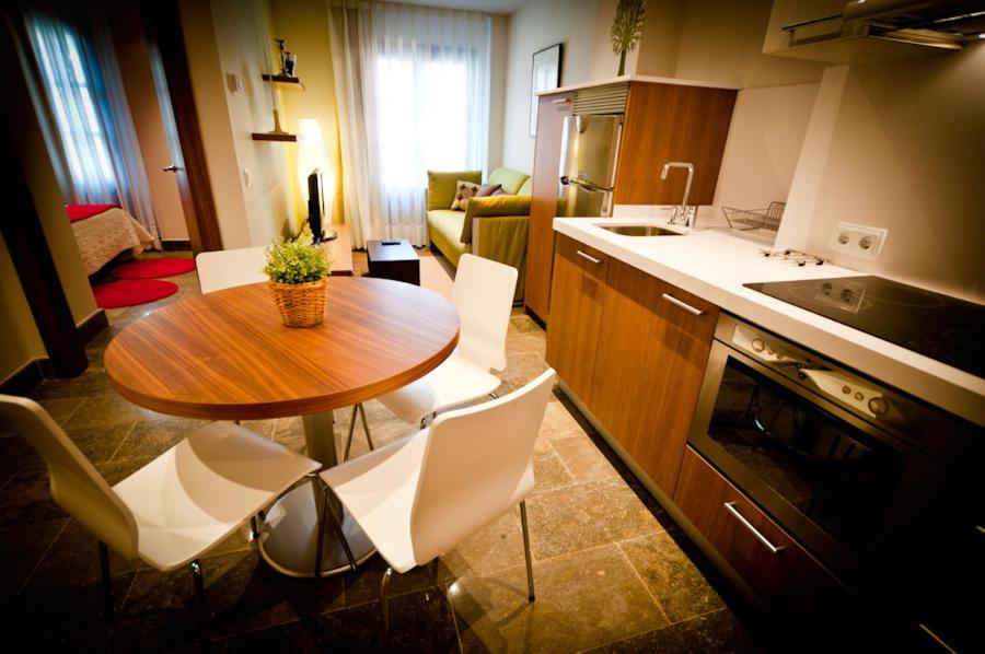 a kitchen with a wooden table and white chairs at Apartamentos Abaco in Llanes