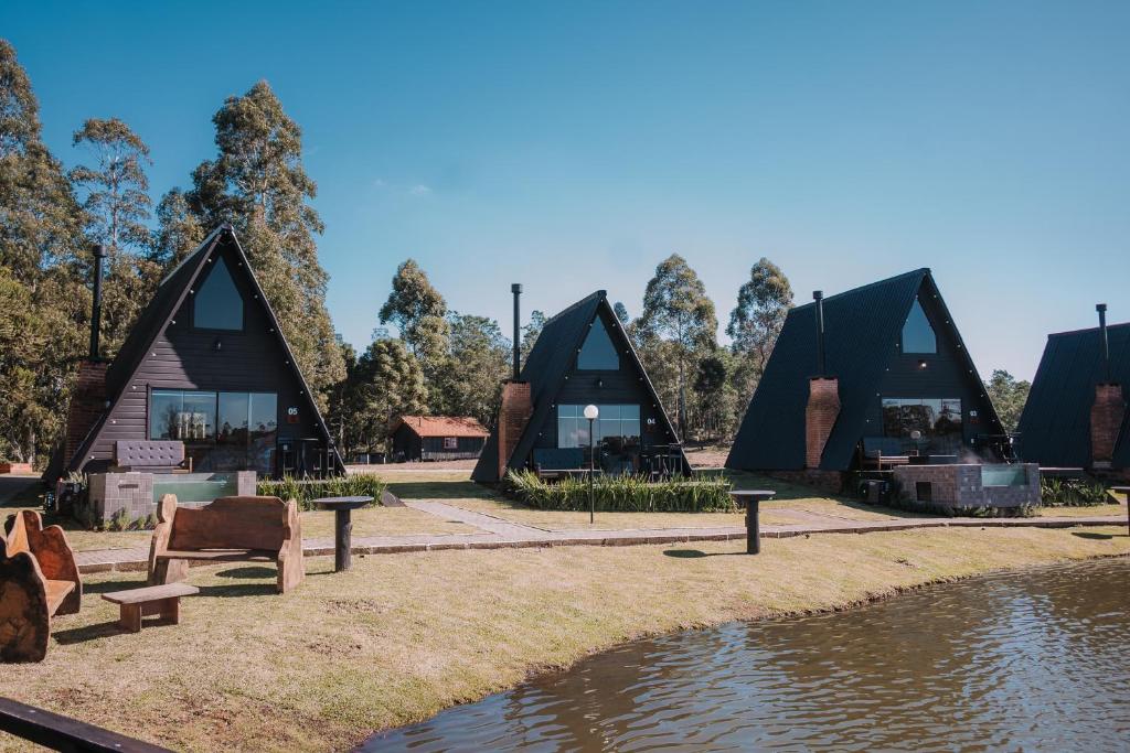 a group of three houses with a pond and trees at Vila Gramado in Gramado
