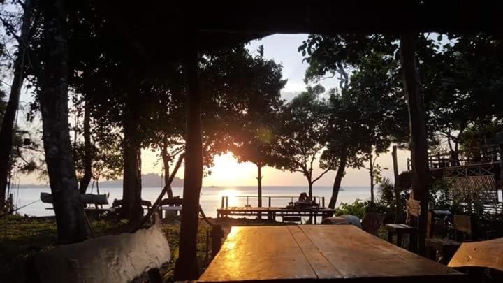 Una mesa de picnic con la puesta de sol sobre el agua en Moonshine Phayam beach resort & restaurant, en Ranong
