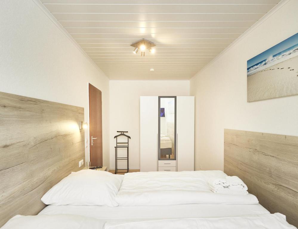 a bedroom with a large white bed with a wooden headboard at Rotesand - 117 in Cuxhaven