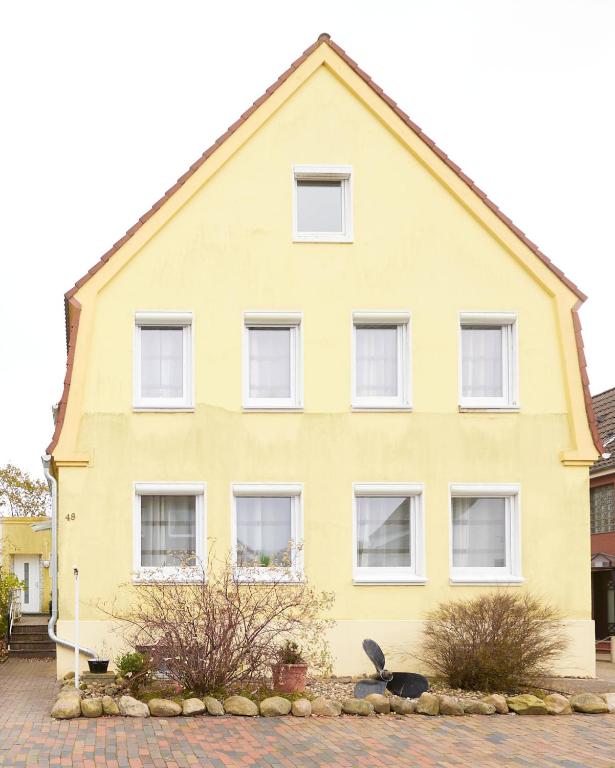 a yellow house with white windows on a street at Strandhus Cuxi - 2 in Cuxhaven