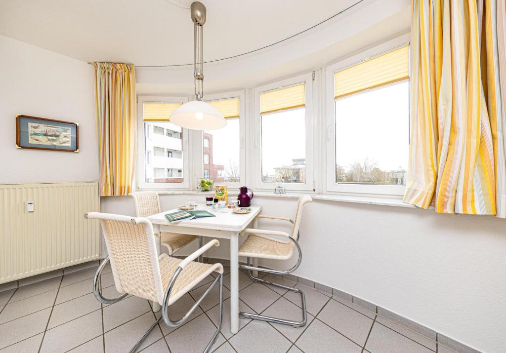 a dining room with yellow curtains and a white table and chairs at Seeterrassen - 12 in Cuxhaven