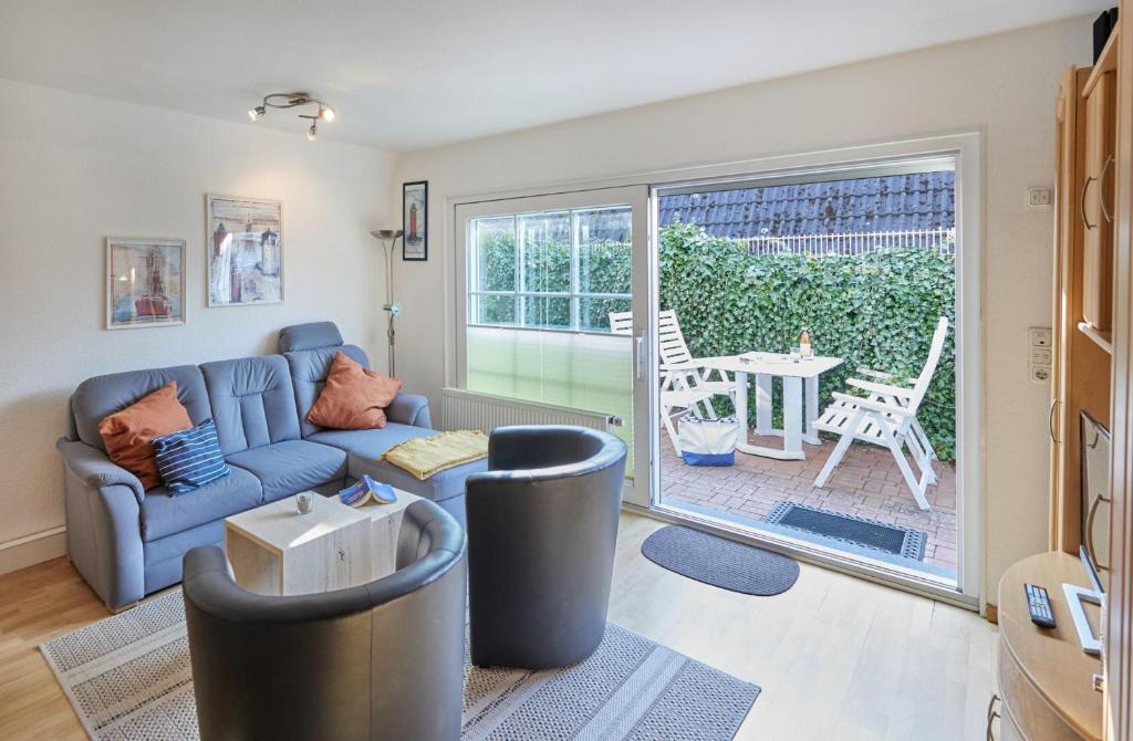 a living room with a blue couch and a sliding glass door at Haus Tide in Cuxhaven