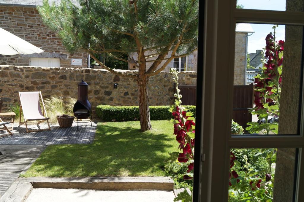 una ventana con vistas a un patio con un árbol en La maison d'hôtes Ty Pic en La Vicomté-sur-Rance