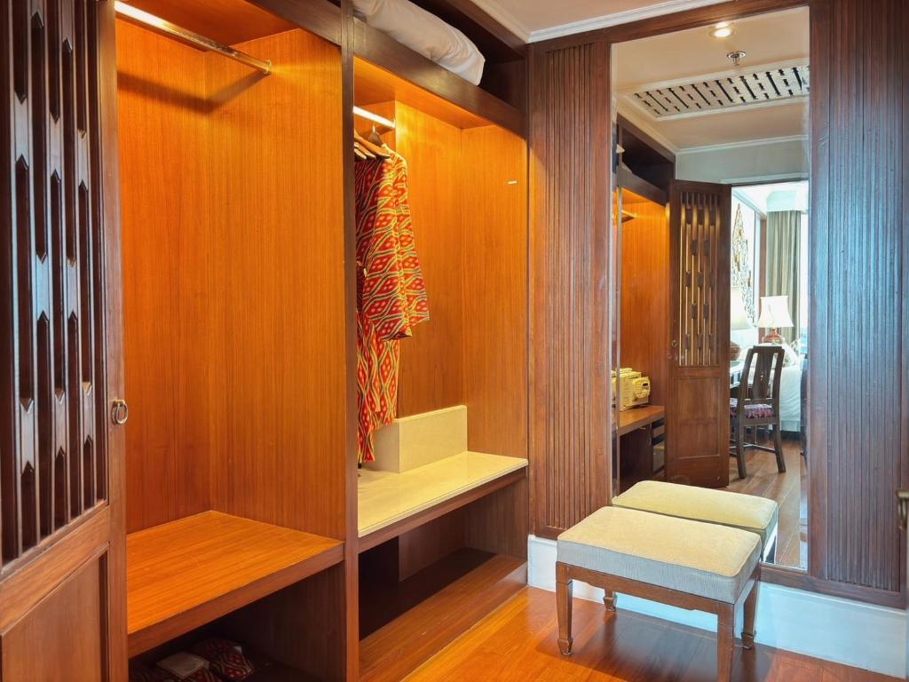 A walk-in wardrobe with open hanging rails, shelving, a bench and a full-length mirror.