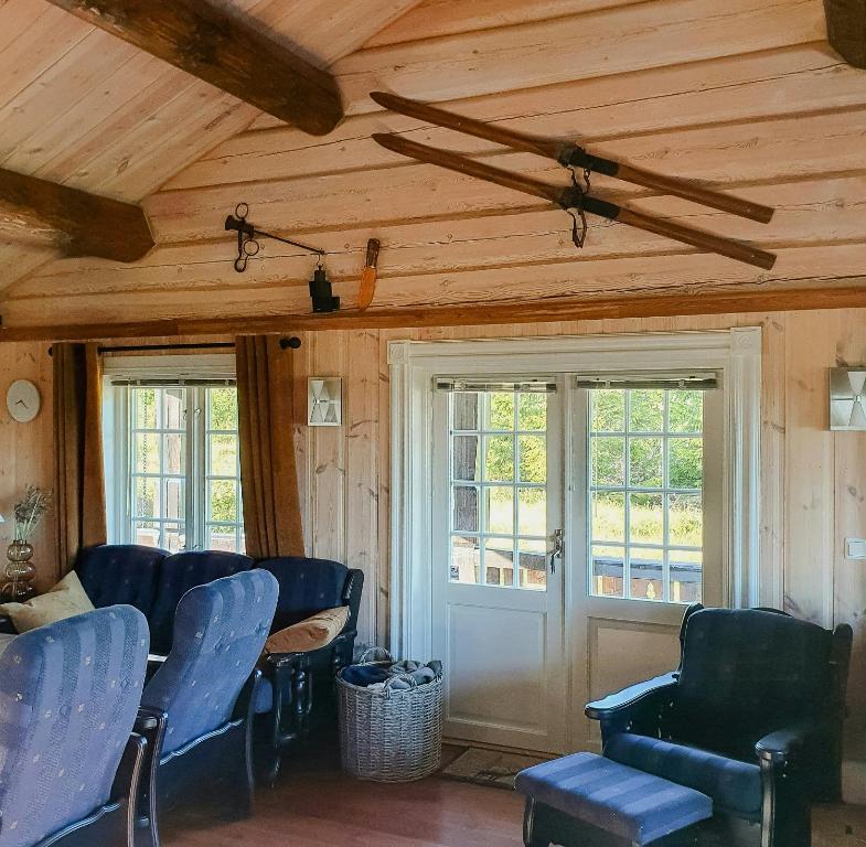 a room with blue chairs and a door and windows at Log Cabin Near Høgevarde With Mountain Views in Granheim