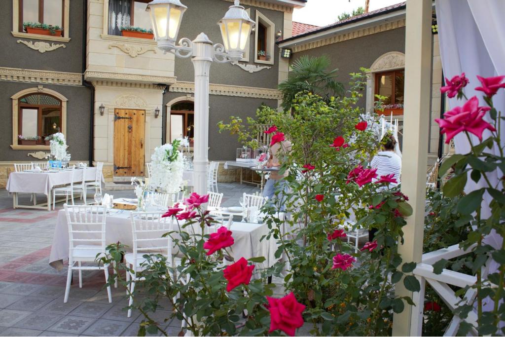 a patio with white tables and red roses at Museum Luxury Guest House in Sheki