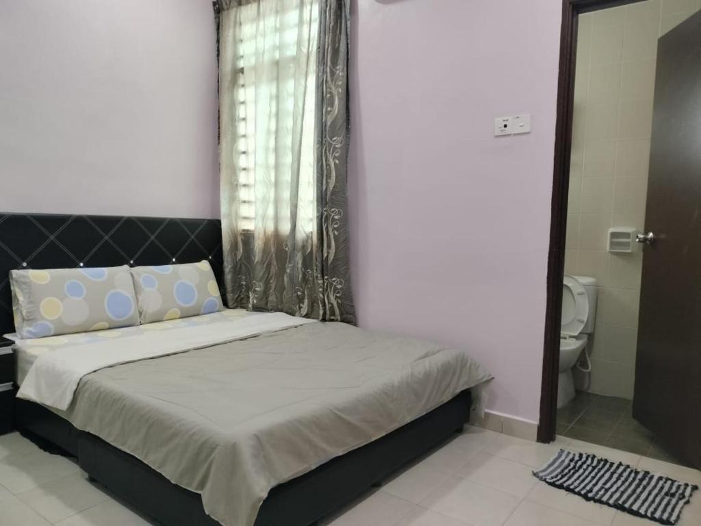 a bedroom with a bed and a window and a toilet at Purple TownHouse 9pax 3R2B Wifi in Sekinchan