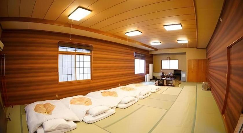 a large room with a row of white pillows at Hotel Miyoshino Annex in Sano