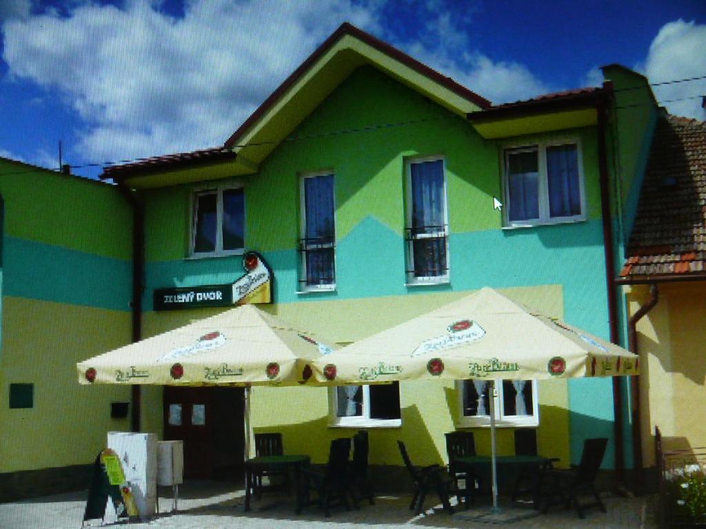 a green building with two umbrellas in front of it at Penzion Zelený Dvor in Veľká Lomnica