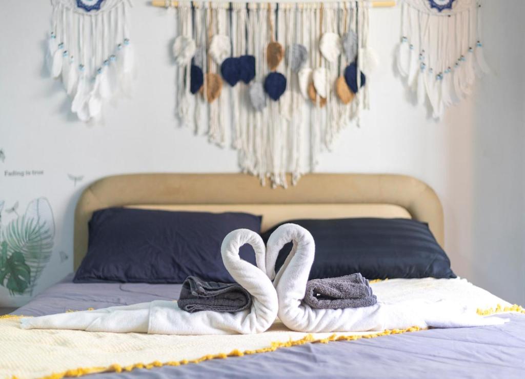 two white swans are sitting on top of a bed at Urban Escape-Prime Nimman Studio in Chiang Mai