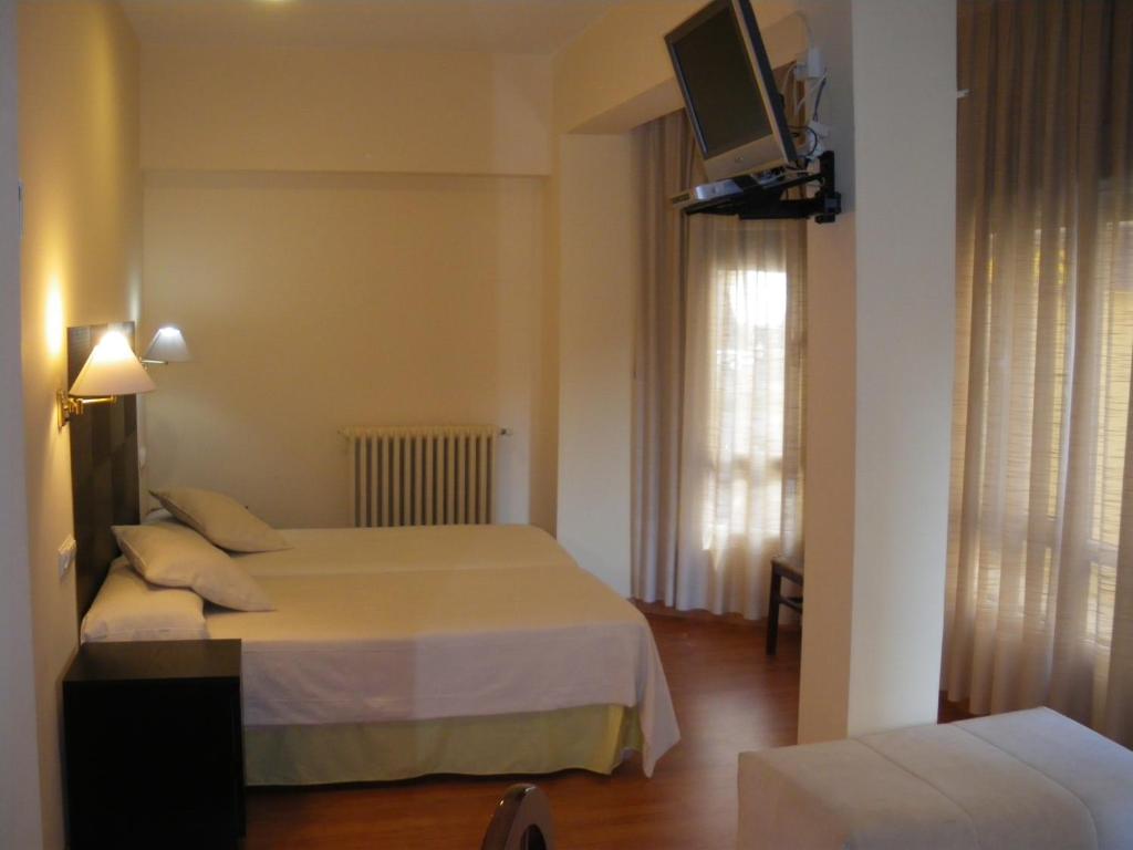 Habitación de hotel con 2 camas y TV en Hostal Ruiz, en Soria