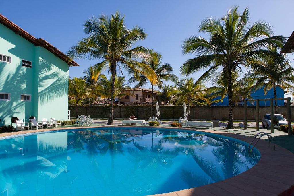 una piscina frente a una casa con palmeras en DAPRAIA - APART TAPERAPUAN PRAIA VILLAGE, en Porto Seguro