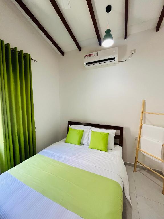 a bedroom with a bed with green curtains at Celestial Negombo Resort Villa 10 in Negombo