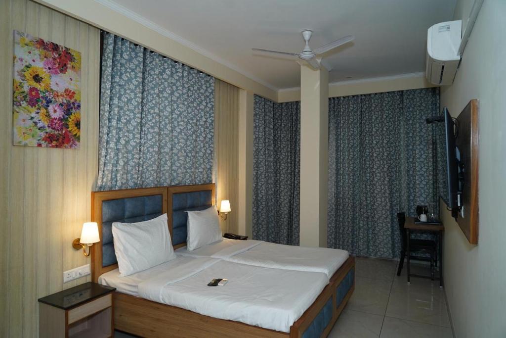 a bedroom with a bed and a tv and curtains at Hotel Northern View in Chandīgarh