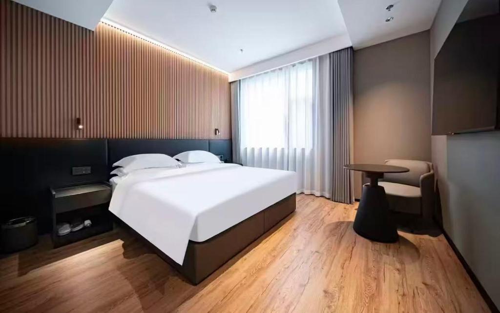 a bedroom with a large white bed and a table at Xihe Langyue Hotel Beijing Changying Tianjie Branch in Beijing