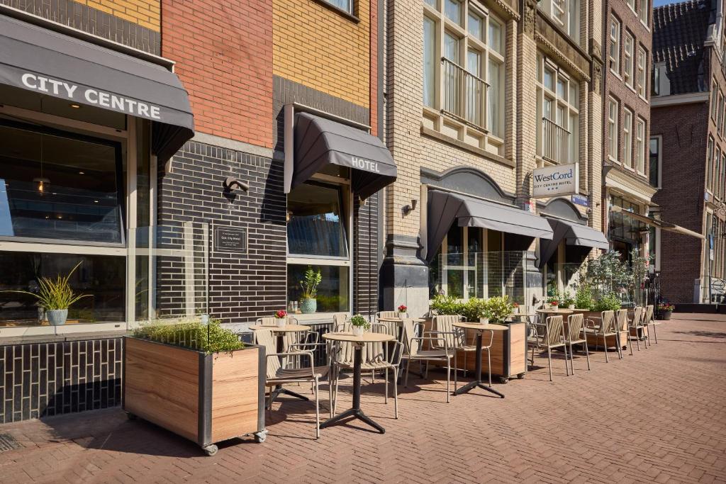 a street with tables and chairs in front of a city centre at WestCord City Centre Hotel in Amsterdam