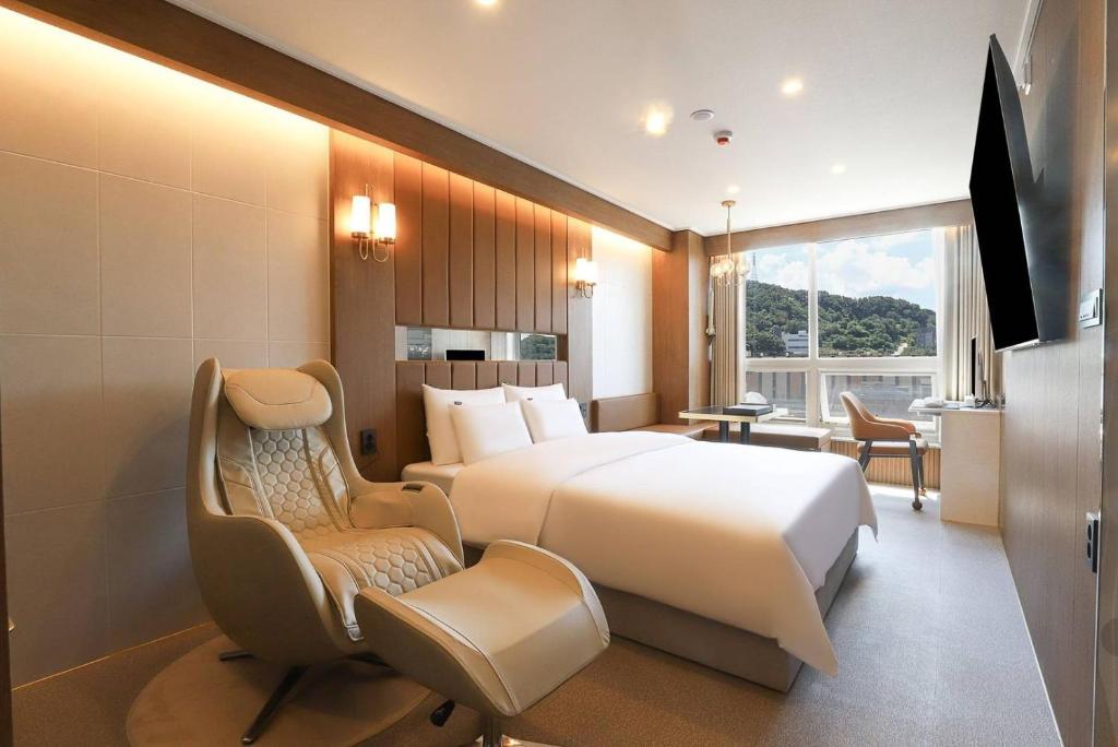 a hotel room with a bed and a chair and a tv at Wonju Urban Brown Hotel in Wonju