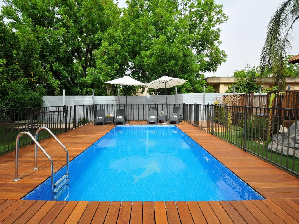 una piscina en una terraza de madera con sombrillas en Villa & Lodge Bat Galil en Yesod Hamaala