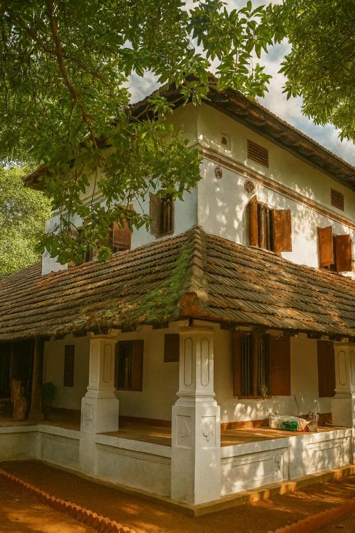 a large white house with a roof at Seclude Karthika Nivas, Thrissur in Trichūr