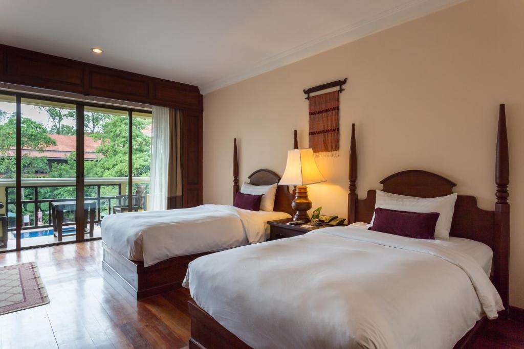 a hotel room with two beds and a balcony at Prince Angkor Hotel & Spa in Siem Reap
