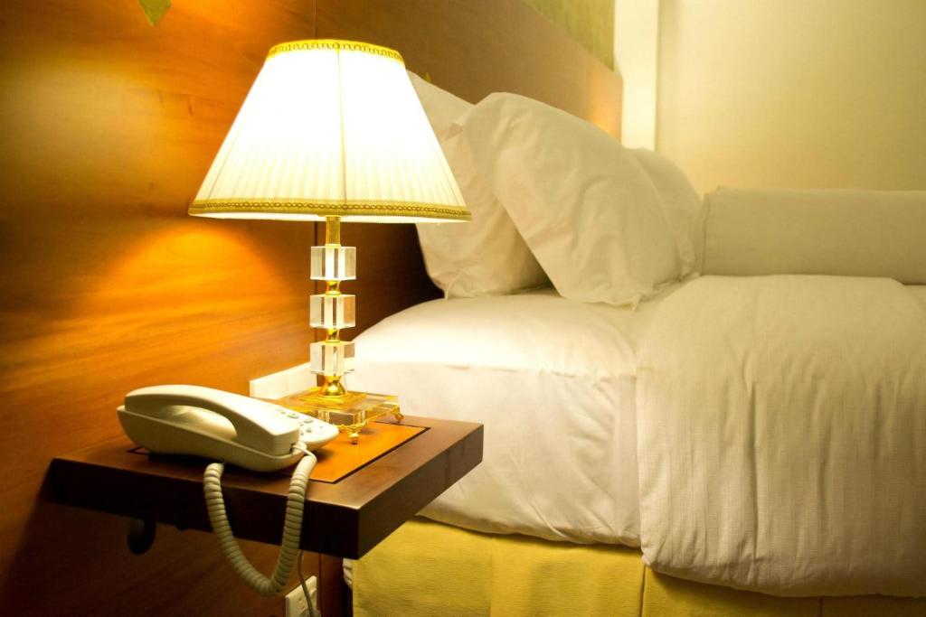 a bed with a phone and a lamp on a table at Deluxe 4BR Penthouse By Unique Towers in Colombo