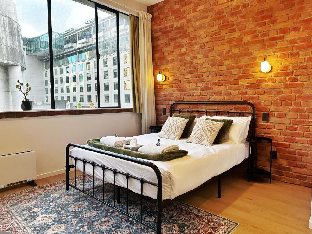 a bed in a room with a brick wall at Skytower views, Wi-Fi, washer & dryer!! in Auckland