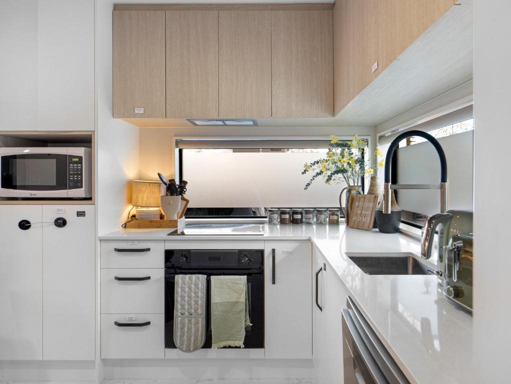 a white kitchen with a sink and a microwave at Apartment on Short ! in Christchurch