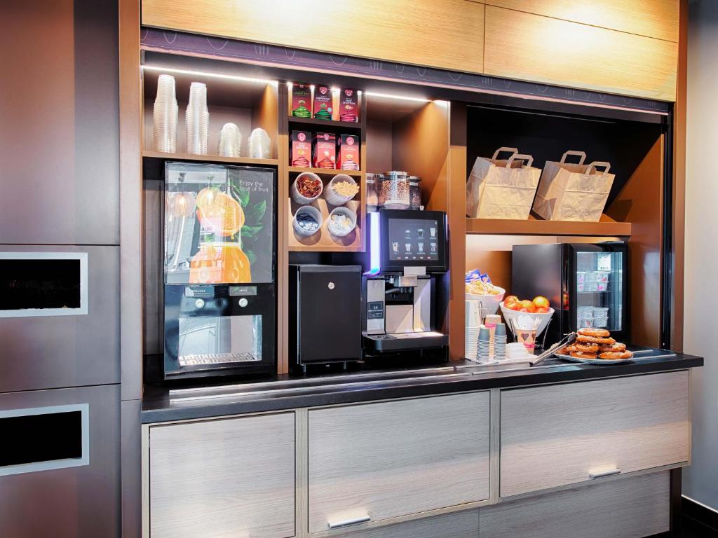 a coffee shop with a counter with food and drinks at B&B Hotel Augsburg-West in Augsburg