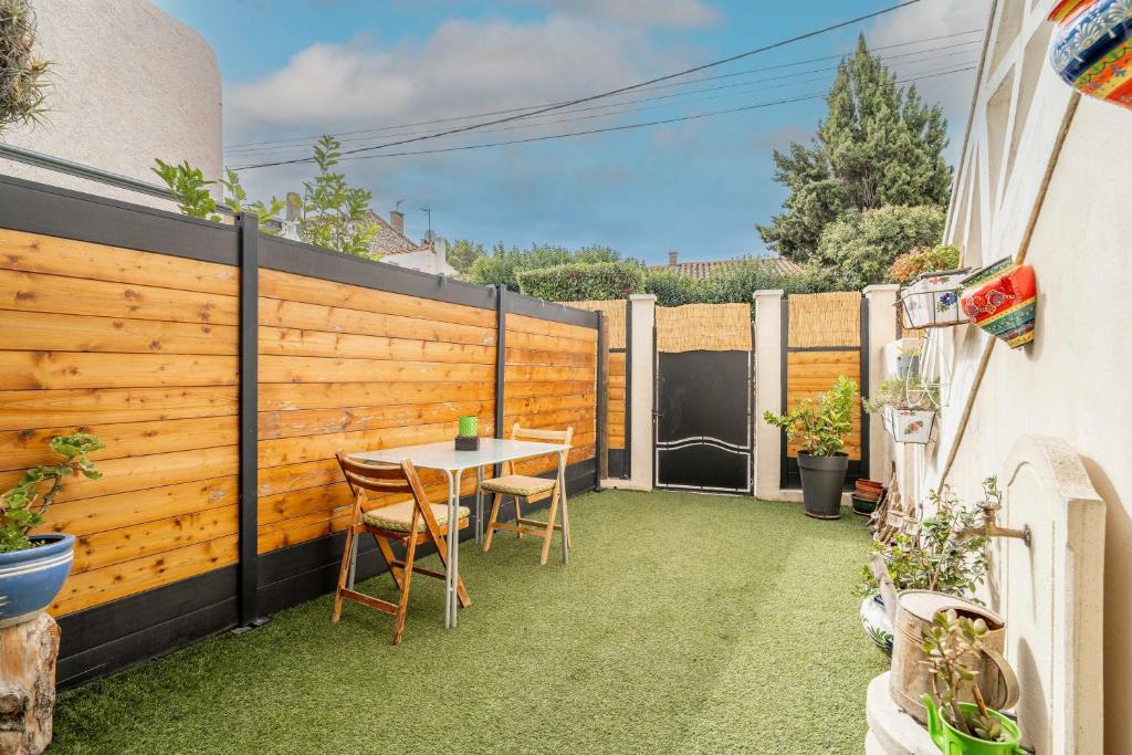 eine Terrasse mit Tisch und Stühlen und einem Zaun in der Unterkunft Les Pieds dans l'Aude in Cuxac-dʼAude