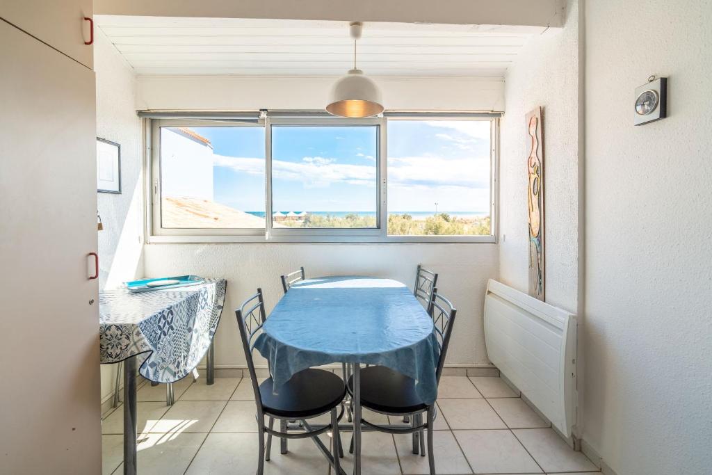 ein Esszimmer mit einem blauen Tisch und Stühlen in der Unterkunft Les Balcons de la Méditerranée in Narbonne-Plage