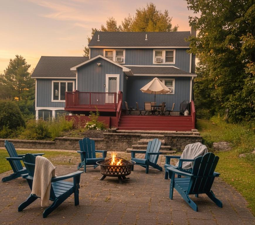 a group of chairs around a fire pit in front of a house at 3BR Lake Luzerne Retreat with Game Room & Hot Tub in Lake Luzerne
