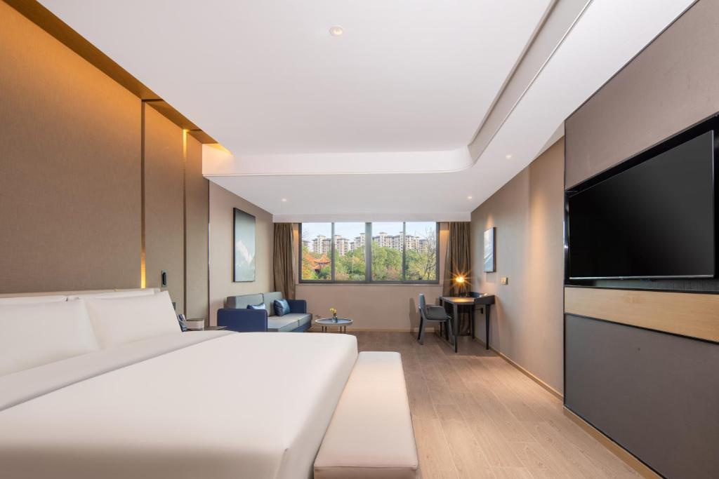 Una habitación de hotel con una cama grande y un televisor de pantalla plana. en Mercure Nanjing Sun Yat-sen Mausoleum, en Nanjing