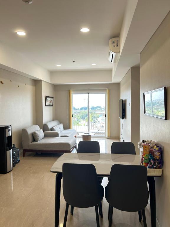 ein Wohnzimmer mit Tisch und Stühlen und einer Couch in der Unterkunft Podomoro Delipark Apartemen Cozystay Empire Tower 3BR Medan in Medan