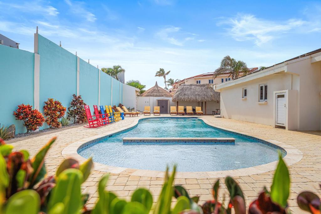 a swimming pool in a yard with colorful chairs at 6BR & 6BA 5 Mins to Beach at Alegria Villa by Bocobay in Palm-Eagle Beach