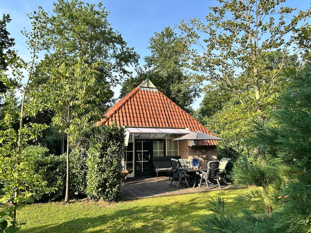 Ce cottage dispose d'une cour avec une table et des chaises. dans l'établissement Recreational cottage with lots of privacy, large forest garden!, à IJhorst