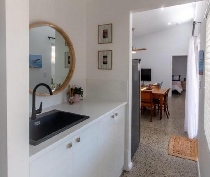 a kitchen with a sink and a mirror and a table at Sou Wester in Lancelin