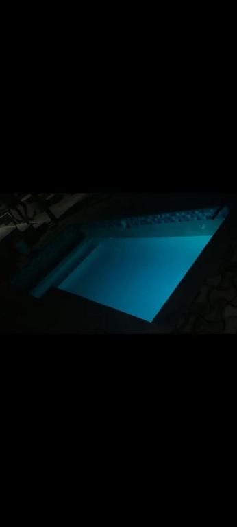 a blue swimming pool in a dark room at The Hope Apartments in Nelspruit