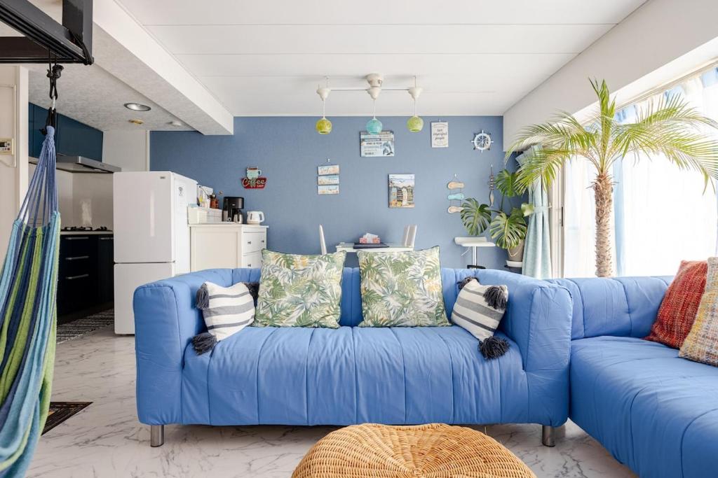 Un sofá azul en una sala de estar con una pared azul. en Onjjukuオーシャンビューコンドミニアム最上階角部屋, en Onjuku