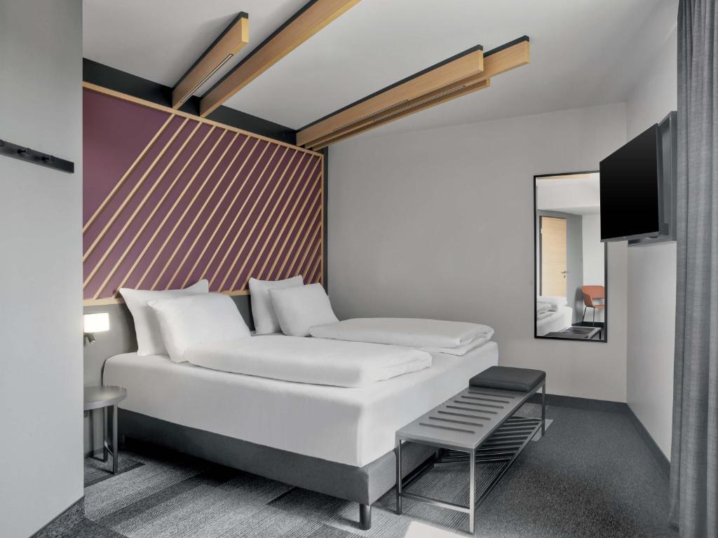 a bedroom with a white bed and a mirror at B&B HOTEL Bielefeld-City in Bielefeld