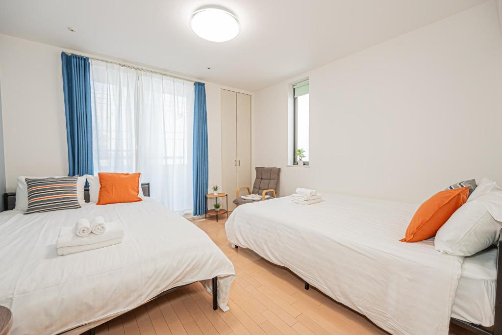 two beds in a bedroom with blue curtains at 301 6 mins walk from Higashi-Jujo Station Comfortable 1 bedroom apartment on the 3rd floor Direct access to Akihabara and Ueno in Tokyo