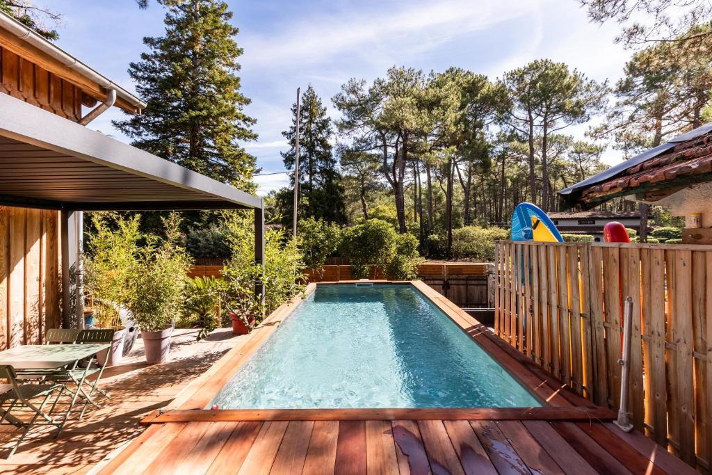 una piscina en un patio trasero con terraza de madera en Studio entre lac et foret, en Lacanau