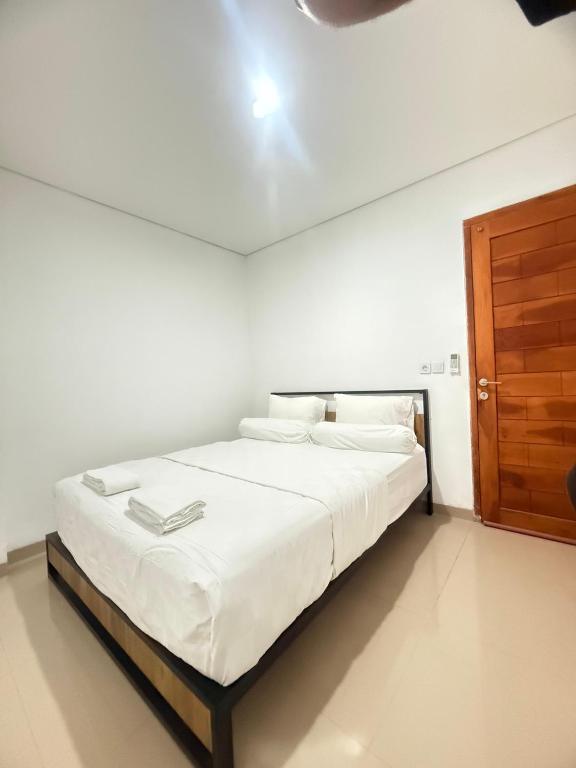 a bedroom with a bed with white sheets and a wooden door at Home Stay Room in Bali Near Sanur Beach in Sanur