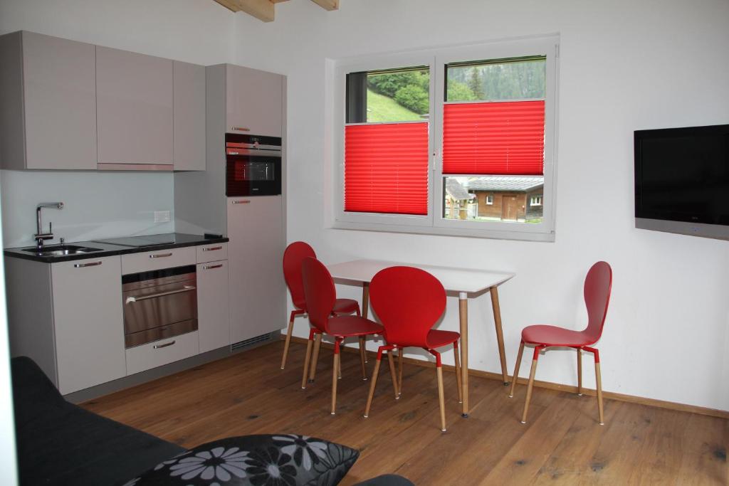 a kitchen with red chairs and a table in a room at Haus Steiner in Göschenen