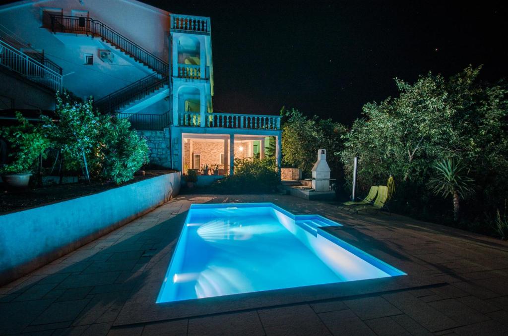 a swimming pool in front of a house at night at Apartments Slavica in Dramalj